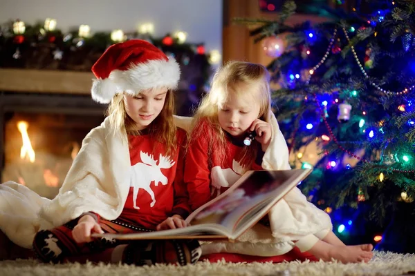 Systrarna läser bok på julafton — Stockfoto