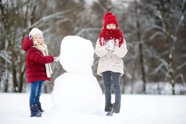 Små flickor bygga en snögubbe — Stockfoto