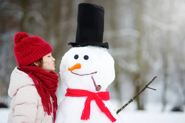 Schattig meisje gebouw een sneeuwpop — Stockfoto
