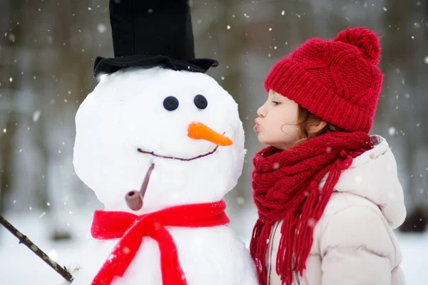 Klein meisje bouwen sneeuwpop — Stockfoto