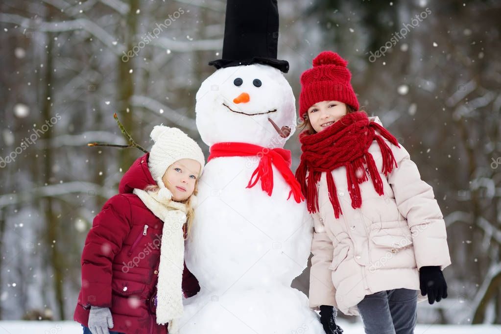 Little girls building snowman 
