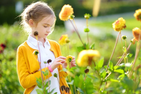 Little girl sniffing at yellow flowers — Stock Photo, Image