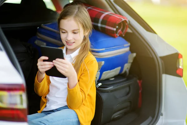 Gadis di bagasi mobil membaca ebook — Stok Foto