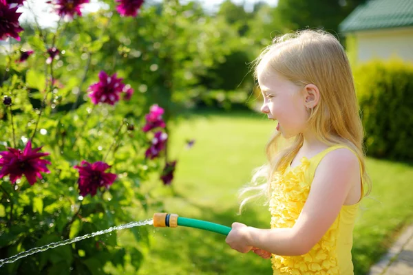 夏の日に庭の花に水をまくかわいい女の子 晴れた日にガーデン ホースを使用して子を Mommys リトル ヘルパー — ストック写真