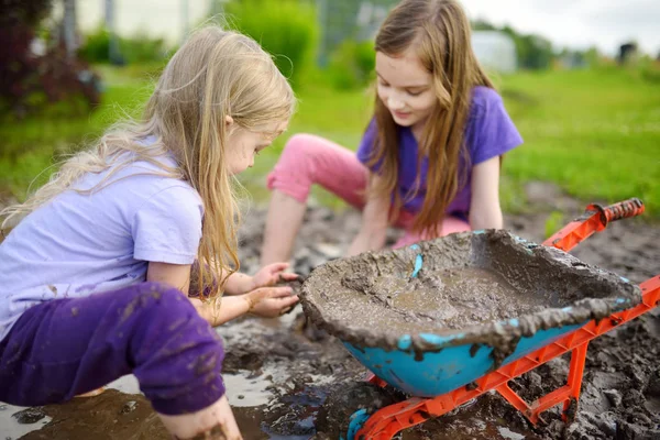 大きなウェットで遊んで面白いの二人の少女は 日当たりの良い夏の日に水たまりを泥します 子供は 粘性土を掘りながら汚い 厄介なゲーム アウトドア — ストック写真