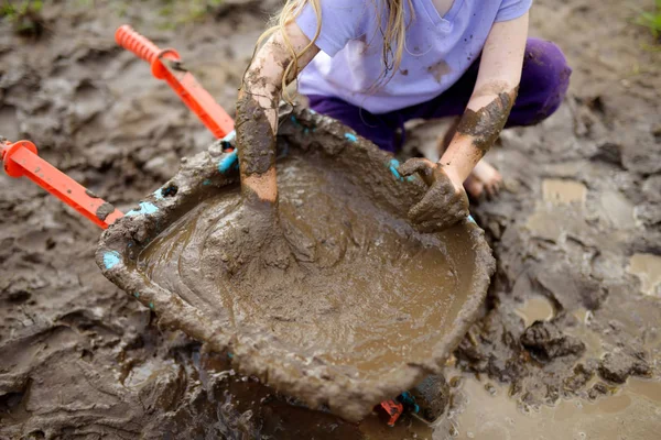 日当たりの良い夏の日に大きな濡れた泥の水たまりで遊んで面白い女の子 粘性土で掘りながら汚れた得ることの子 厄介なゲーム アウトドア — ストック写真