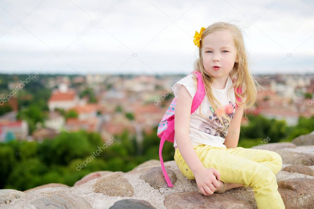 Cute little girl enjoying a view of Vilnius city from the Gediminas hill. Exploring tourist attractions with kids.