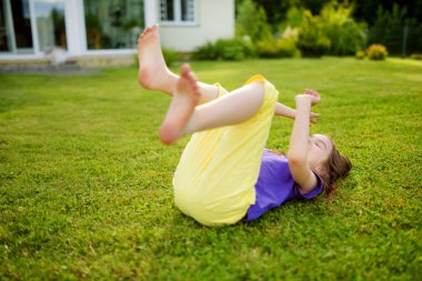 Sevimli küçük kız güneşli yaz akşamı arka bahçede bir çim üzerinde eğleniyor. Çocuklar için yaz etkinlikleri.