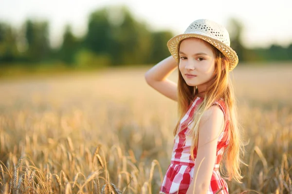 暖かく 日当たりの良い夏の夜の麦畑でうれしそうに歩いて麦わら帽子を身に着けている愛らしい少女 サンセット フィールドでかわいらしい子供 — ストック写真