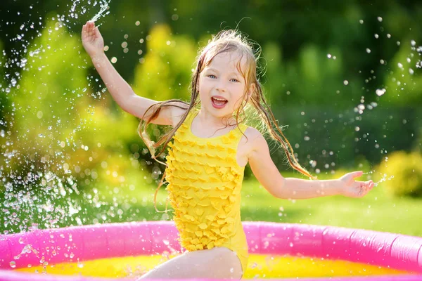 膨脹可能な赤ん坊のプールで遊ぶ愛らしい少女 幸せな子供の夏の暑い日にカラフルな庭遊び中心ではね 子供のための夏の活動 — ストック写真