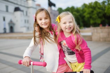 Küçük çocuk scooter bir şehir parkı güneşli yaz akşamı binmek için öğrenme. Sevimli küçük kız Silindirler binmek. Etkin boş ve çocuklar için açık spor.