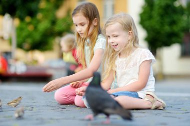 İki sevimli küçük kız besleme birds yaz gününde. Güvercinler ve Serçeler açık havada besleme çocuk. Çocuklarla etkin boş.