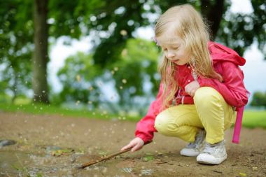 Sevimli küçük kız güzel yaz günü açık havada üzerinde bir su birikintisi içinde oynamaya. Çocuklar için etkin yaz eğlence.
