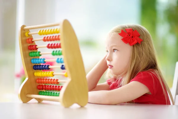 Little girl playing with wooden abacus — Stock Photo, Image