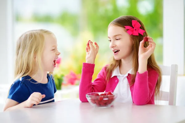 Små flickor äta hallon hemma — Stockfoto