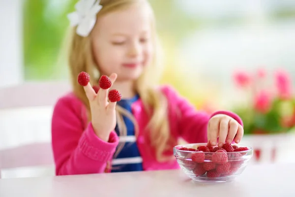 Pretty little girl eating raspberries — Stock Photo, Image