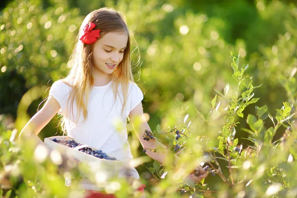 Kleines Mädchen pflückt frische Beeren — Stockfoto