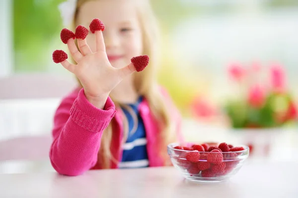 Mooi klein meisje thuis eten van frambozen — Stockfoto