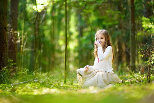 Malá holčička, trhání květin v lese — Stock fotografie