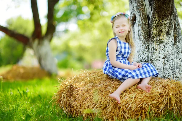 Little girl sitting on haystack — Stock Photo, Image