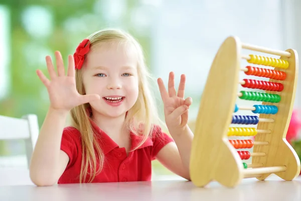 Kleines Mädchen spielt mit hölzernem Abakus — Stockfoto