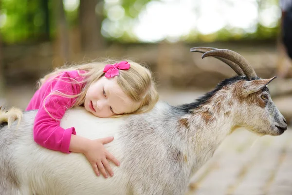 Sevimli küçük kız sevişme keçi — Stok fotoğraf
