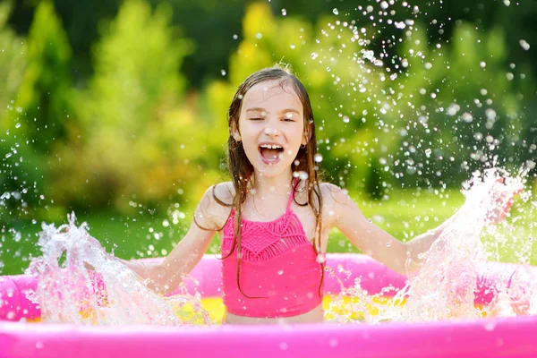 Kleines Mädchen spielt im aufblasbaren Pool — Stockfoto