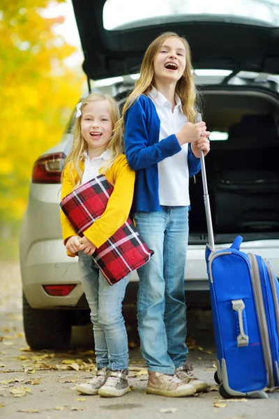 二人の愛らしい女の子の車にスーツケースをパッキング — ストック写真