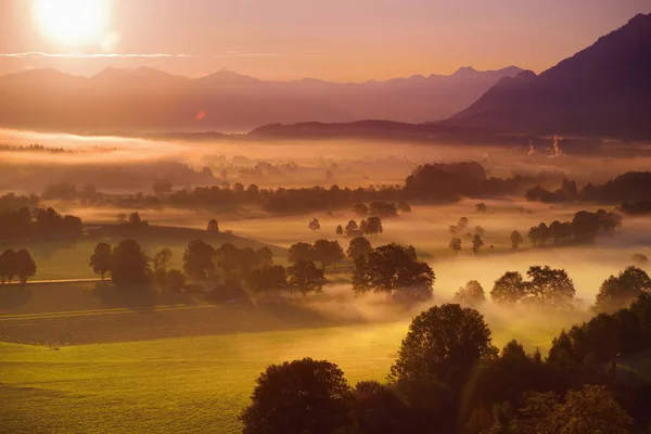 ババリア地方の小さな村の朝息をのむ風景は霧に覆われています ドイツの雄大な山と日の出でババリア地方のアルプスの眺望 — ストック写真