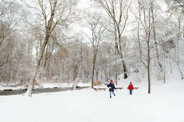 İki sevimli genç kız güzel kış parkında birlikte eğleniyorlar. Karda oynayan sevimli kız kardeşler. Çocuklar için kış aile aktiviteleri.