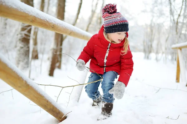 美しい冬の公園で楽しんでいる愛らしい若い女の子。雪の中で遊ぶかわいい子供。子供連れの家族のための冬の活動. — ストック写真