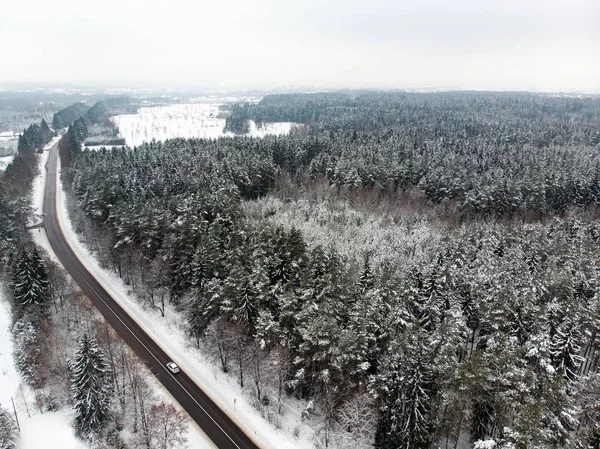 stock image Beautiful aerial view of snow covered pine forests and a road winding among trees. Rime ice and hoar frost covering trees. Scenic winter landscape in Vilnius, Lithuania.