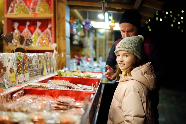 Carino ragazza che sceglie dolci sul tradizionale mercatino di Natale a Riga, Lettonia. Ragazzo che compra caramelle e biscotti a Natale . — Foto Stock