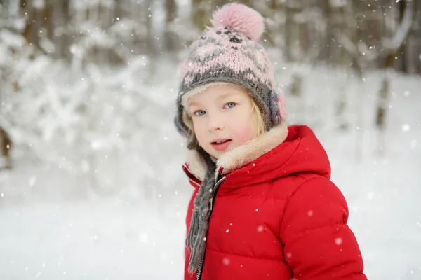 Adorable young girl having fun in beautiful winter park. Cute child playing in a snow. Winter activities for family with kids. — Stock Photo, Image