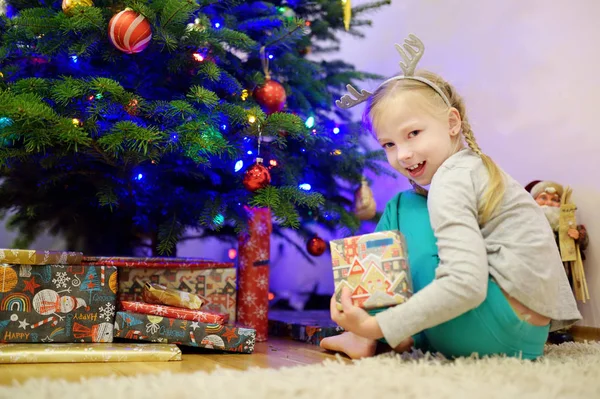 Entzückendes kleines Mädchen schmückt den Weihnachtsbaum mit bunten Glaskugeln. Den Weihnachtsbaum beschneiden. — Stockfoto