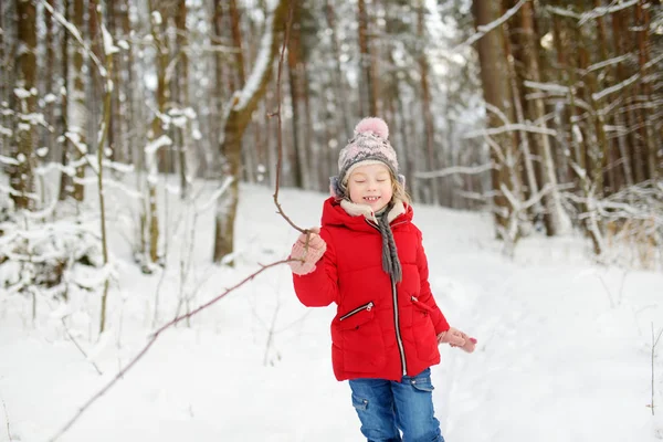 美しい冬の公園で楽しんでいる愛らしい若い女の子。雪の中で遊ぶかわいい子供。子供連れの家族のための冬の活動. — ストック写真