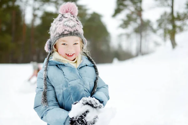 Söt ung flicka som har roligt i vackra vinterpark. Söta barn som leker i snö. Vinteraktiviteter för barnfamiljer. — Stockfoto