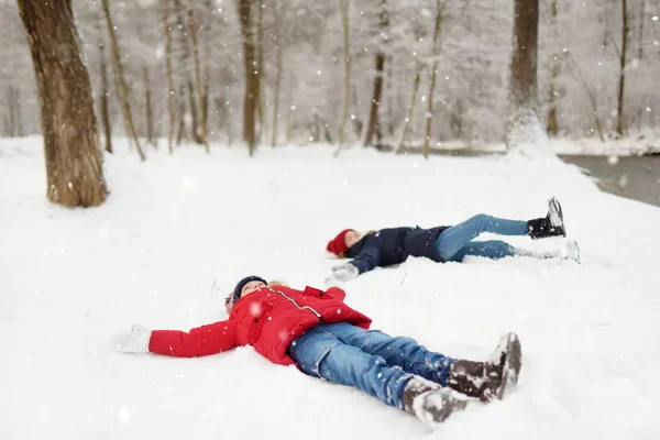 Due adorabili ragazze si divertono insieme nel bellissimo parco invernale. Sorelle carine che giocano nella neve. Attività invernali per famiglie per bambini . — Foto Stock