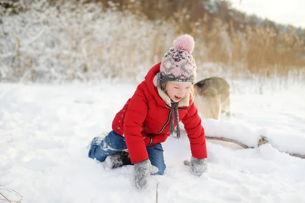 Garota adorável se divertindo perto de belo lago congelado. Criança bonito brincando em uma neve . — Fotografia de Stock