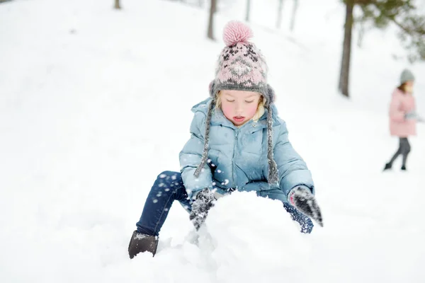 美しい冬の公園で楽しんでいる愛らしい若い女の子。雪の中で遊ぶかわいい子供。子供連れの家族のための冬の活動. — ストック写真