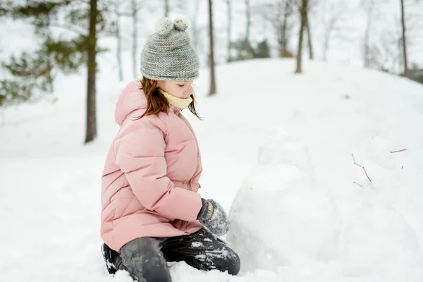 아름다운 겨울 공원에서 놀고 있는 귀여운 소녀. 귀여운 아이가 눈 속에서 놀고 있습니다. 아이들 과 함께 가족을 위한 겨울 활동. — 스톡 사진