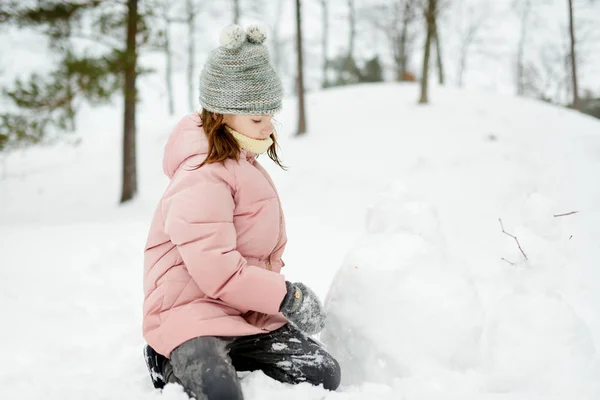 美しい冬の公園で楽しんでいる愛らしい若い女の子。雪の中で遊ぶかわいい子供。子供連れの家族のための冬の活動. — ストック写真