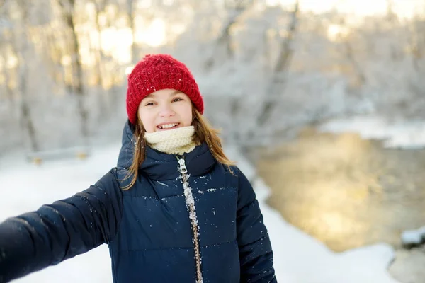 Очаровательная молодая девушка развлекается в красивом зимнем парке. Милый ребенок, играющий в снегу. Зимние развлечения для семьи с детьми . — стоковое фото