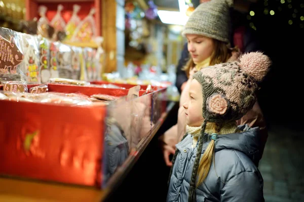 Cute young sisters choosing sweets on traditional Christmas market in Riga, Latvia. Kids buying candy and cookies on Xmas. — Stock Photo, Image