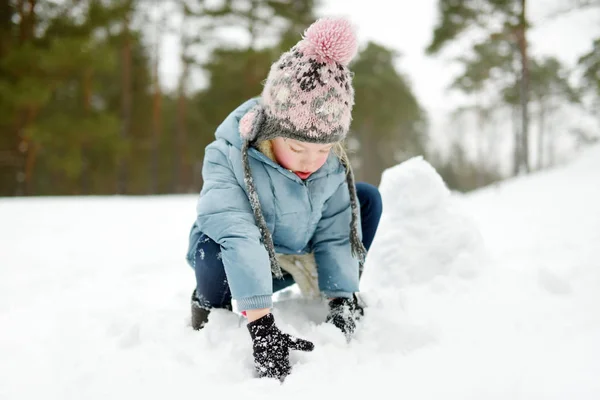 Adorable young girl having fun in beautiful winter park. Cute child playing in a snow. Winter activities for family with kids. — Stock Photo, Image