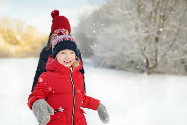 İki sevimli genç kız güzel kış parkında birlikte eğleniyorlar. Karda oynayan sevimli kız kardeşler. Çocuklar için kış aile aktiviteleri. — Stok fotoğraf