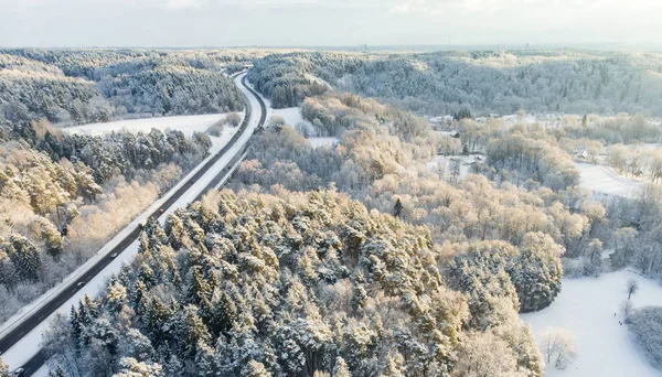 Schöne Luftaufnahme von schneebedeckten Kiefernwäldern und einer Straße, die sich zwischen Bäumen windet. Reifglätte und Raureif bedecken Bäume. malerische Winterlandschaft in Vilnius, Litauen. — Stockfoto