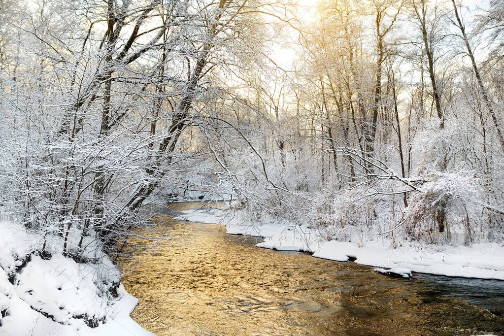 Beautiful view of snow covered forest. Narrow river flowing between snow covered trees. Chilly winter day.