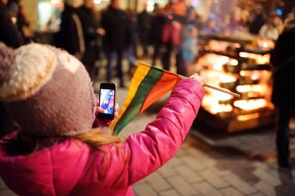 Dítě, které se zúčastnilo oslav obnovení státního svátku ve Vilniusu v Litvě. Oheň je zapálen na Gediminas Avenue v noci 16. února. — Stock fotografie