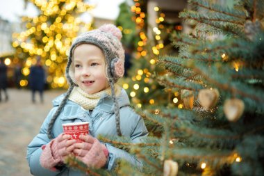 Riga, Letonya 'da geleneksel Noel festivalinde sıcak çikolata içen tatlı genç kız. Çocuk Noel pazarında tatlı, şeker ve zencefilli çöreğin tadını çıkarıyor. Aile ve çocuklarla kış zamanı..
